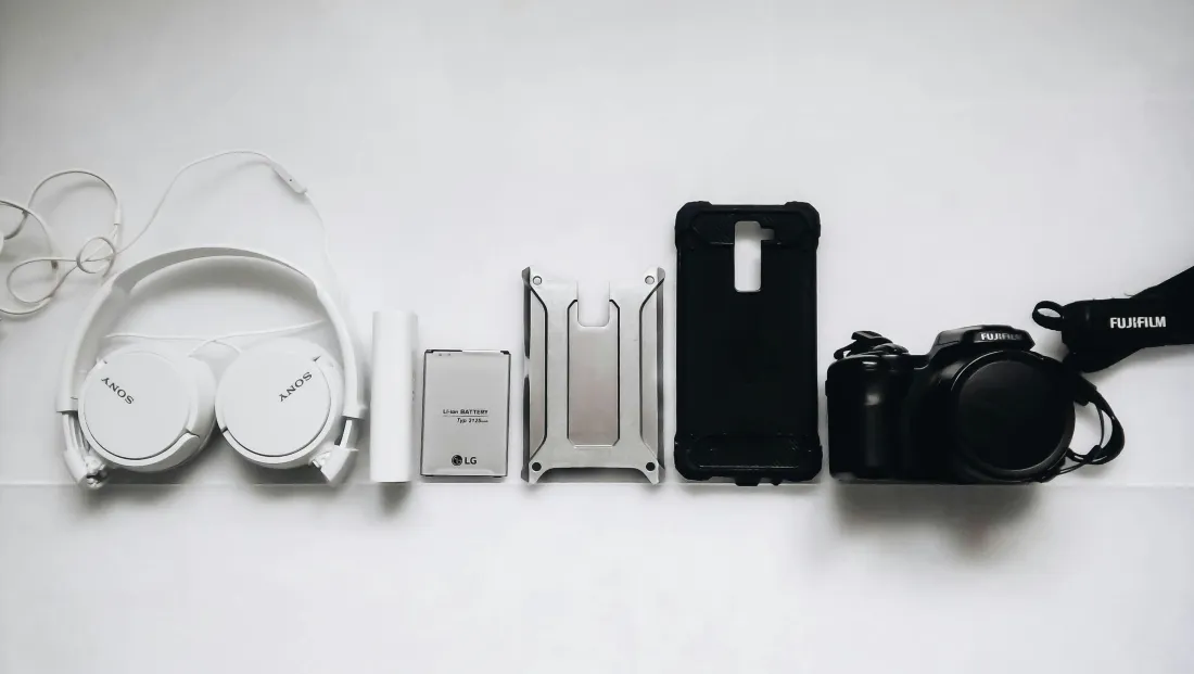 Cuffie, smartphone e fotocamera su un tavolo bianco (foto illustrativa)